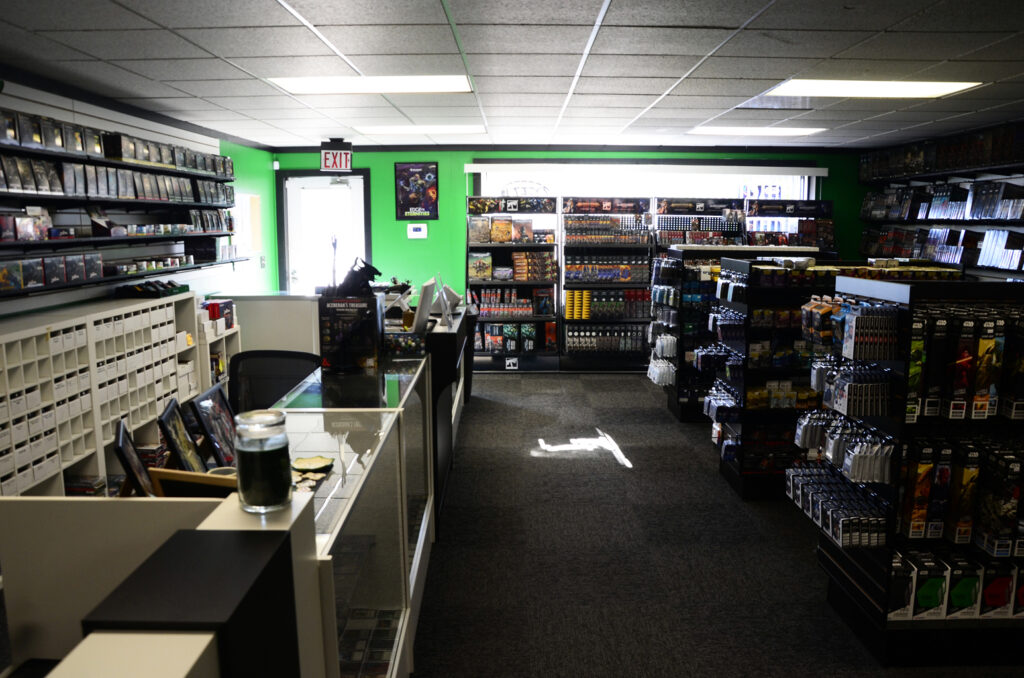 Interior of a video game store: green accent wall, shelves stocked with games, and a checkout counter near the entrance.