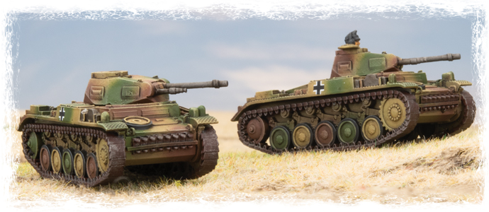 Two camouflage-pattern model tanks on a grassy field under a blue sky.