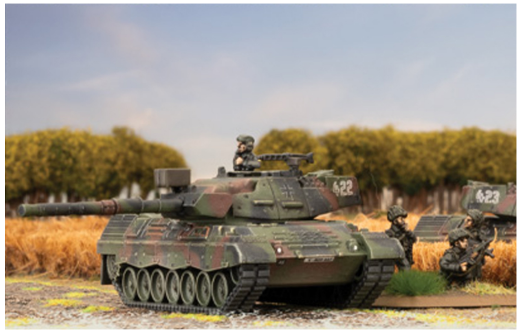 Screenshot 20260416 092816 Frontline Gaming Miniature military diorama: camouflaged tank with soldiers in a field, realistic scenery in the background, as if modeling a battlefield scene.