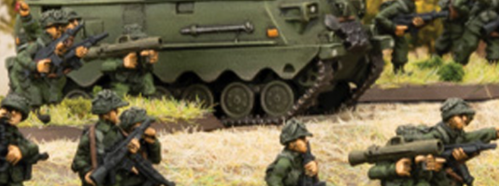 Group of military toy figures aiming guns in front of a green toy tank on a diorama set piece.
