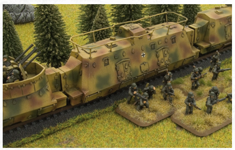 Tabletop miniature scene with a camouflaged armored train and a squad of soldiers advancing through grass and trees.
