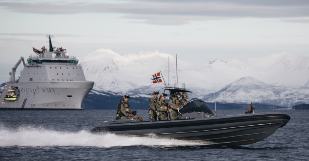 image Frontline Gaming Speedboat with armed crew and a Norwegian flag speeds across icy water, with a large support ship and snow-covered mountains in the background.