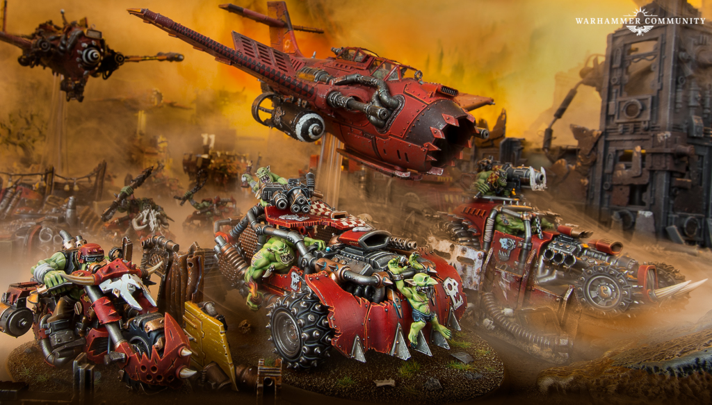 Green orc troops battle on red armored vehicles in a smoky, orange-lit wasteland with ruined buildings; Warhammer Community logo in the top-right corner.