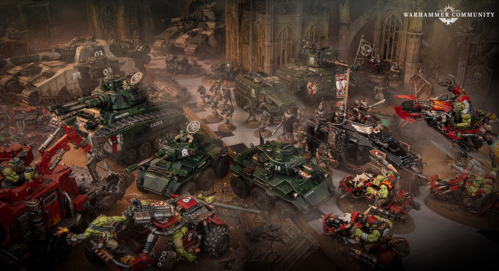 Warhammer battle scene with green orc troops and armored tanks clashing inside a gothic ruins setting, banners flying overhead.