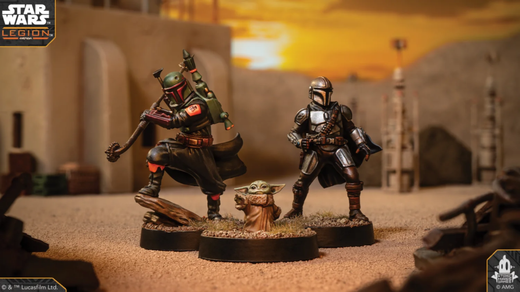 Star Wars: Legion miniatures on a desert battlefield: Boba Fett attacks, Din Djarin stands ready, Grogu between them.