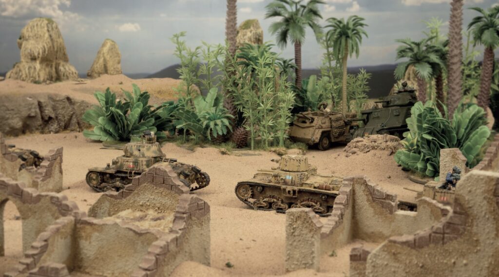 Miniature desert battlefield diorama with several tanks among ruined stone walls and palm trees for a toy scene.