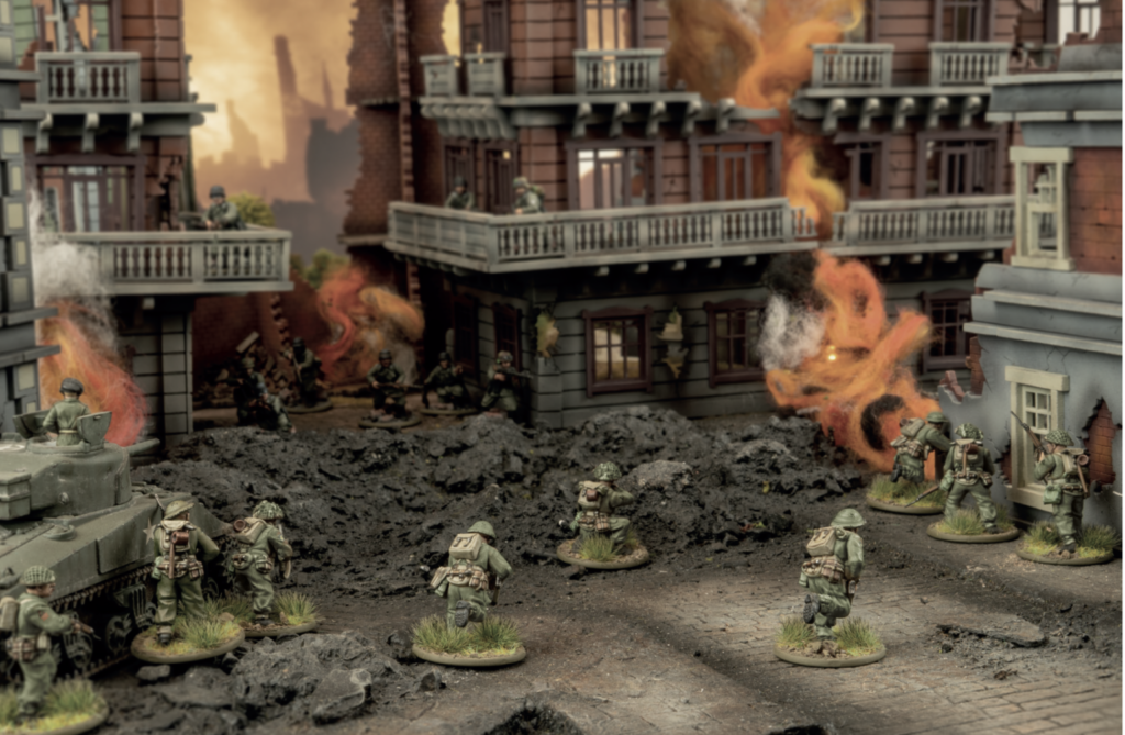 Miniature World War II battle scene with soldiers advancing through a ruined city, smoke and flames erupting from destroyed buildings.