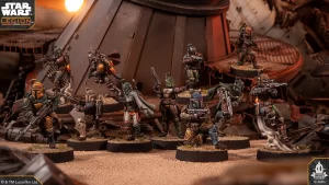 Group of Star Wars: Legion miniatures posed on a sandy battlefield diorama with rubble, weapons drawn, backdrop of industrial ruins (logo top-left).