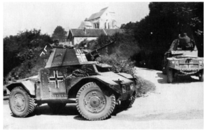 WWII-era German armored car on a dirt road with a cross insignia, and a tank in the background near trees.