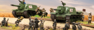 Scale-model battle scene: two green toy tanks labeled 'T 63' and 'T 67' on a rural diorama with soldiers and a railway track behind them