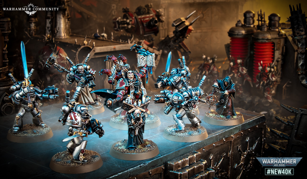 image Frontline Gaming Group of blue-armored Warhammer 40K miniatures on a display diorama, with a dark workshop background and 'Warhammer Community' logo in the corner.