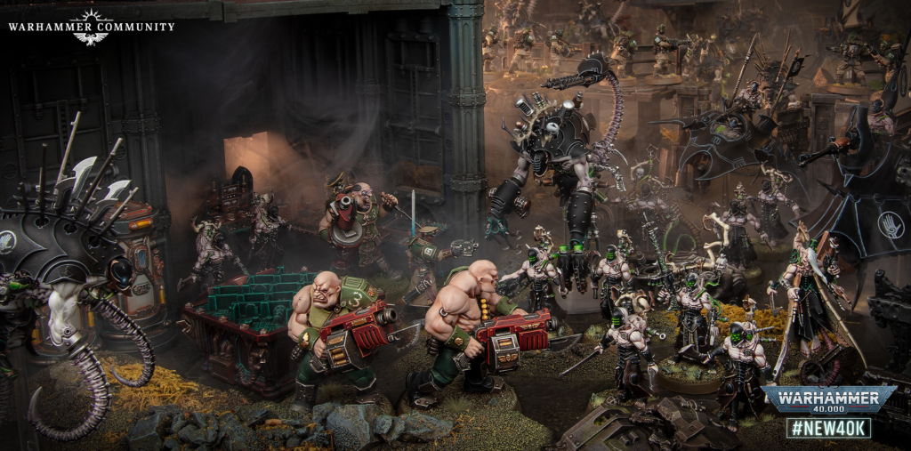 Epic Warhammer 40,000 battle diorama: armored troops clash inside a ruined fortress, with towering monstrous fighters and swarming infantry in dark atmosphere behind a large assembly line of wargear and banners.