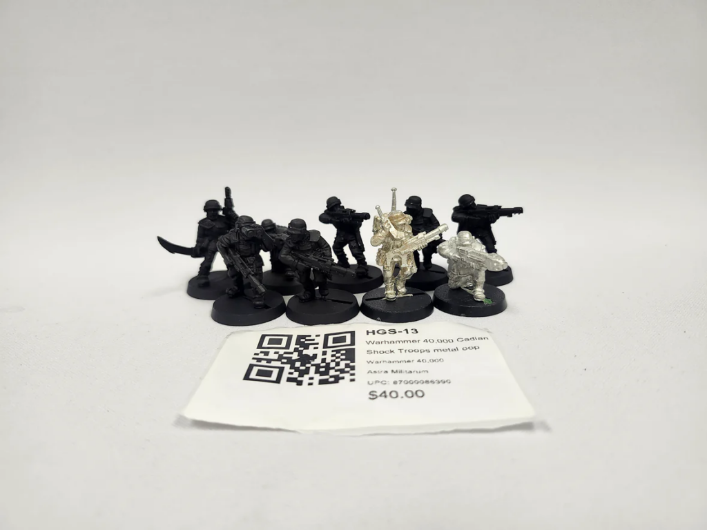 image Frontline Gaming Group of black plastic miniatures arranged on round bases with one silver-painted figure standing out in the front, alongside a price tag and QR code.