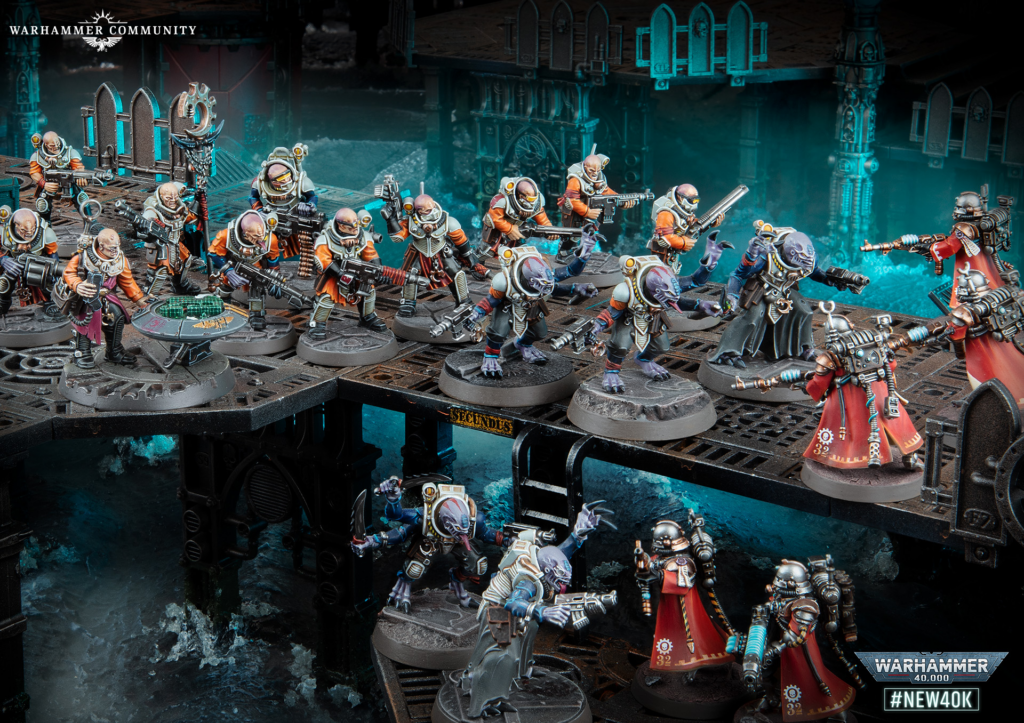 Group of Warhammer 40,000 miniatures in orange and silver armor on a metallic battlefield with teal-lit water in the background, ready for battle.