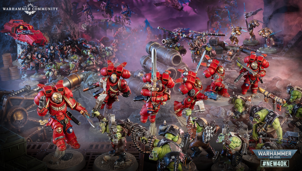 image Frontline Gaming Warhammer 40,000 battle: red-armored Space Marines clash with green Orks amid smoky ruins and heavy weapons.