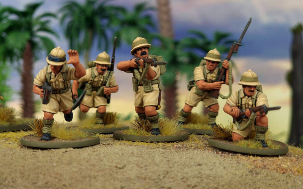 Five beige army-man figurines advance across a sandy diorama with rifles, palm trees in the background.