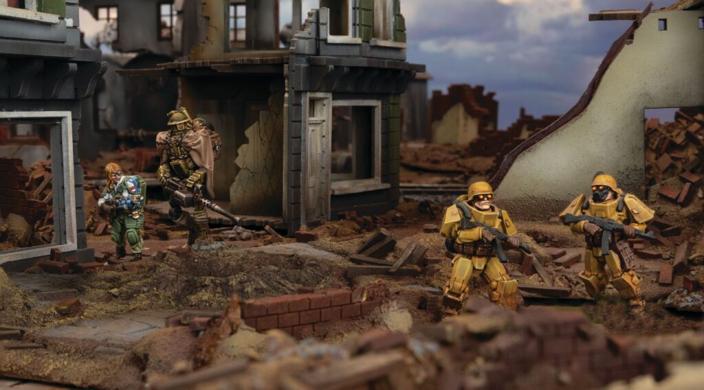 Tabletop diorama of four armored soldiers advancing through a ruined city street.
