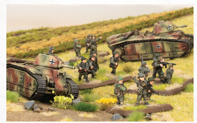 Scale model diorama of WWII German tanks and infantry in a grassy battlefield setting, with soldiers advancing between tanks.
