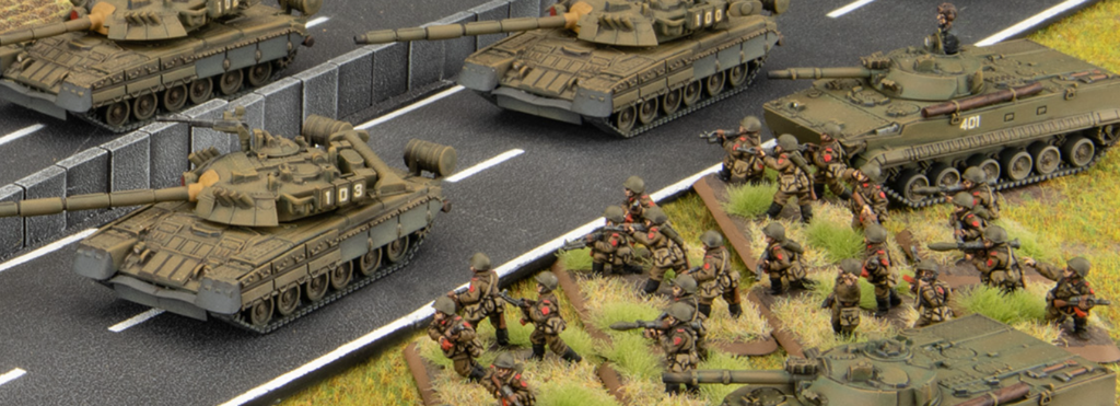 Scale model diorama: tanks on a highway with infantry figures advancing on grass