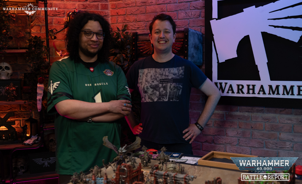 image Frontline Gaming Two men smiling behind a table of Warhammer miniatures in a brick-walled room, with a large Warhammer banner on the right and Battle Report logo.
