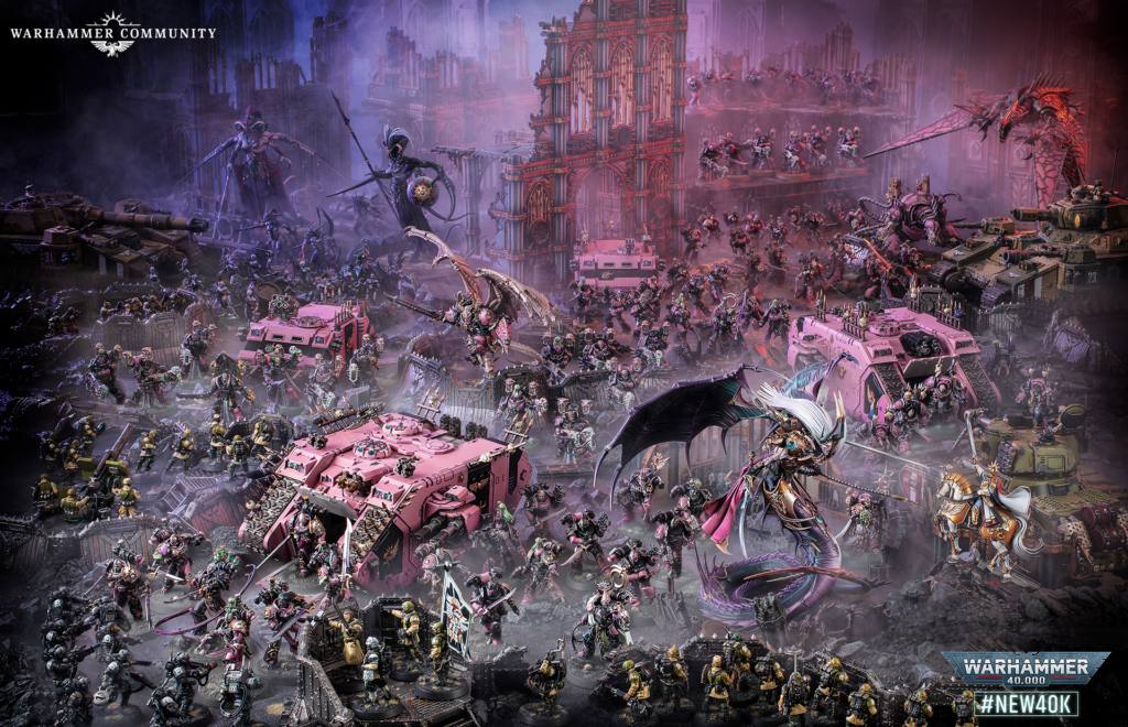 Epic Warhammer 40,000 battle scene with pink armored vehicles, vast infantry, and flying monsters amid a ruined Gothic cityscape. Logo in top left says Warhammer Community.