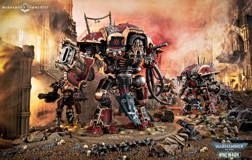 Massive red-armored Warhammer 40K war machines advance through a burning ruin-filled battlefield with skull emblems and gothic architecture nearby.