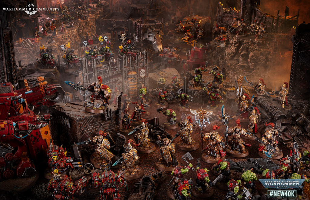 Massive Warhammer 40,000 battle diorama with orc and Imperial forces clashing amid ruined fortifications.