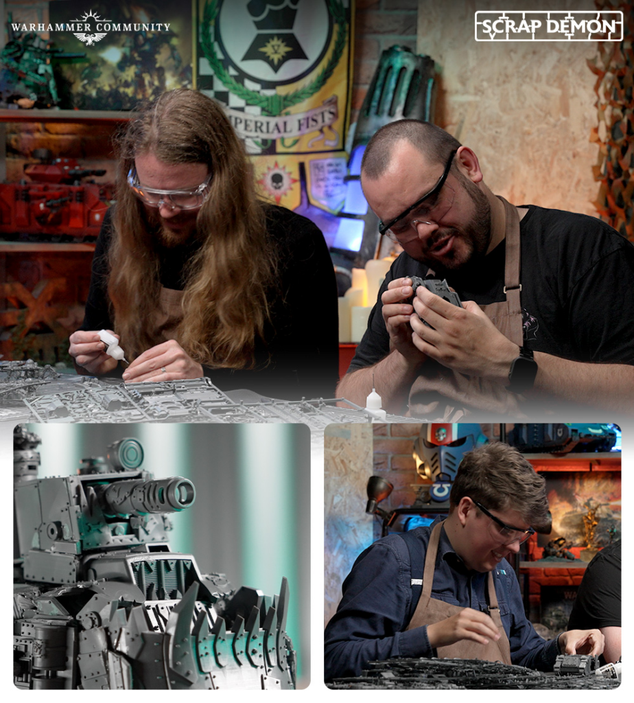 Two hobbyists wearing safety glasses and aprons assemble Warhammer miniatures at a workshop, with a large unfinished model on the table and banners in the background.