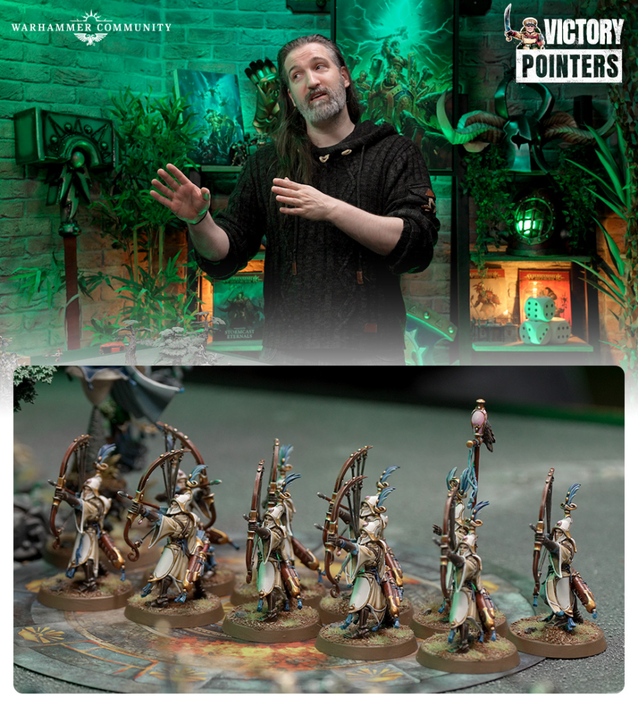 Presenter in a green-lit Warhammer studio with a 'Victory Pointers' logo, foreground shows a row of painted miniature archers on a game board.