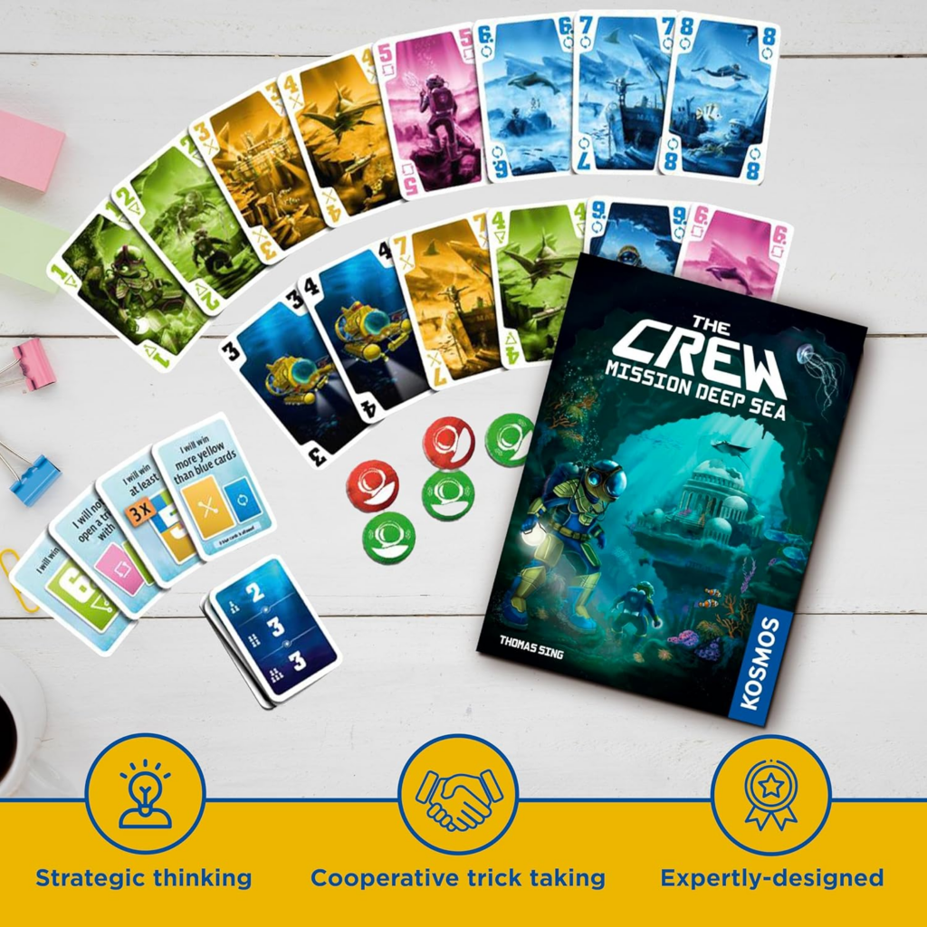 image Frontline Gaming Fanned colorful cards and game pieces on a white table next to The Crew: Mission Deep Sea box.
