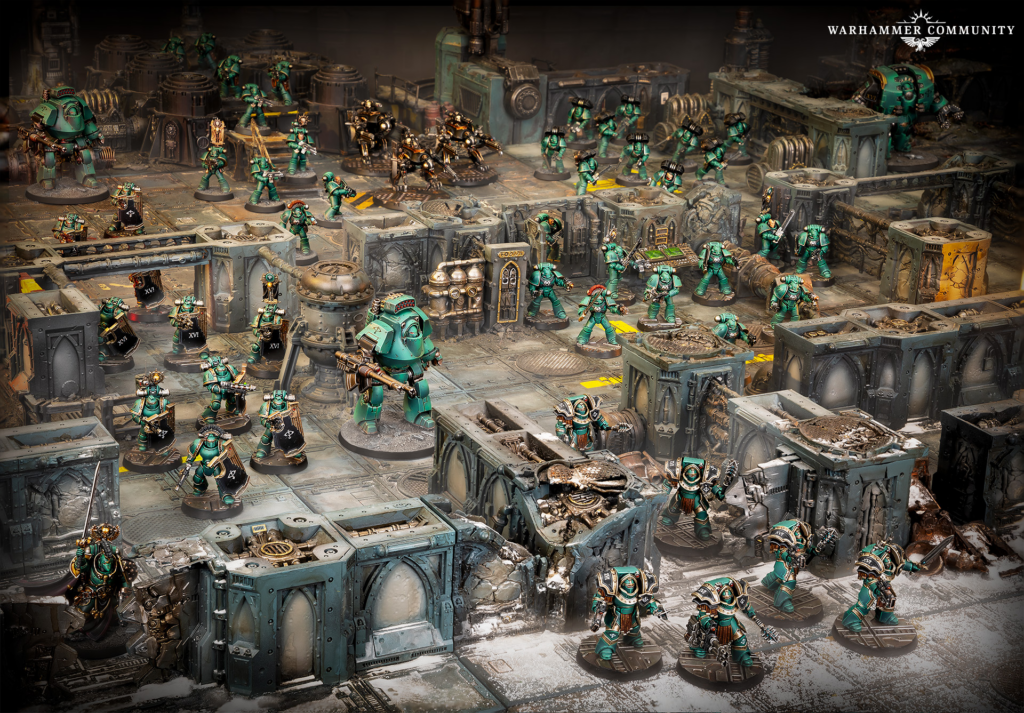 Warhammer battle scene with numerous green-armored Space Marines fighting in a ruined industrial factory.