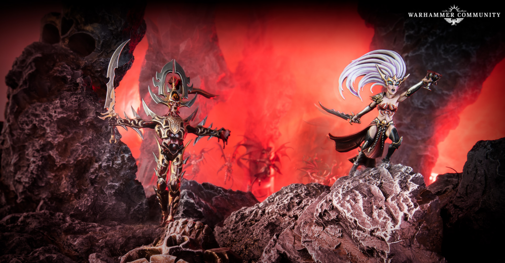 Two ornate Warhammer miniatures stand on jagged lava-gray rocks with a fiery red background; Warhammer Community logo in the top-right corner.