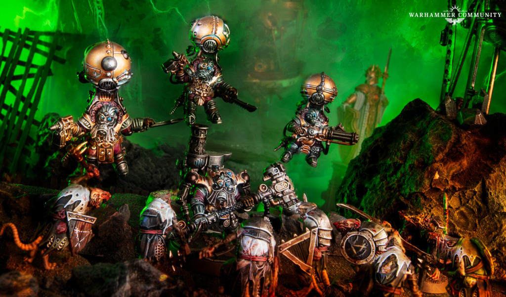 Warhammer diorama: ornate armored miniatures in combat on a rubble-strewn battlefield with green glow and a logo in the corner