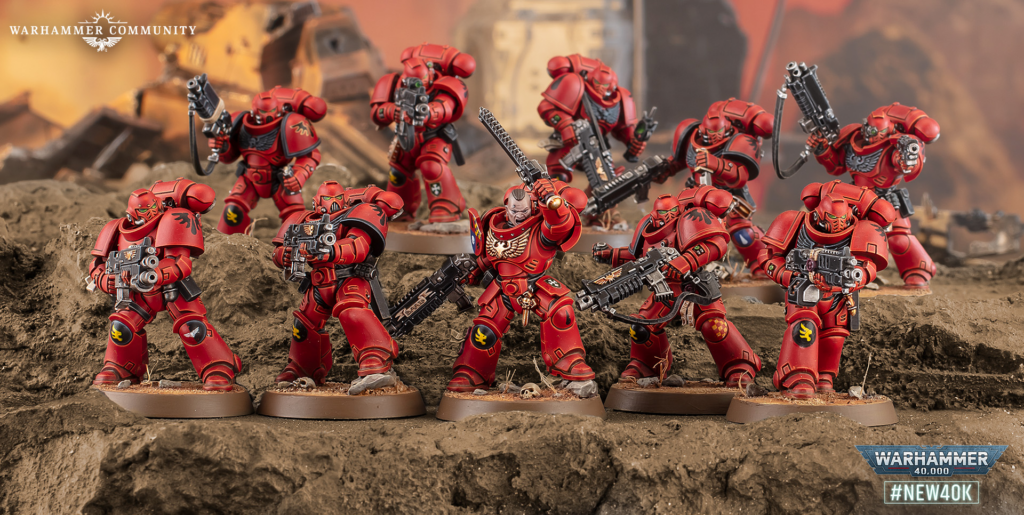 Squad of red-armored Space Marines firing bolters on a rocky battlefield with a Warhammer Community logo in the top-left corner.