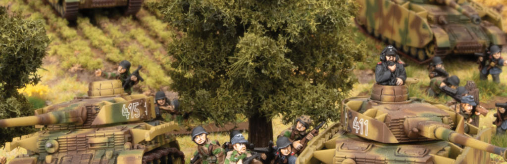 Miniature war diorama with camouflaged tanks labeled 415 and 411 and small soldier figures in a grassy scene under trees