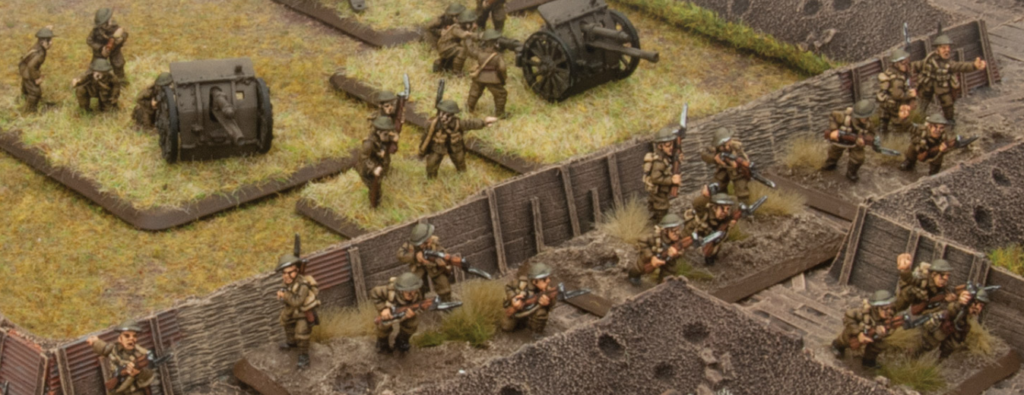 Miniature World War II soldiers in a trench defense armed with rifles with a field cannon on a grassy hill behind them