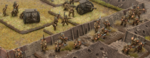 Miniature World War II soldiers in a trench defense armed with rifles with a field cannon on a grassy hill behind them