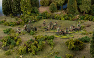 Miniature World War II scene with soldiers operating a field gun in a wooded area in a diorama setting