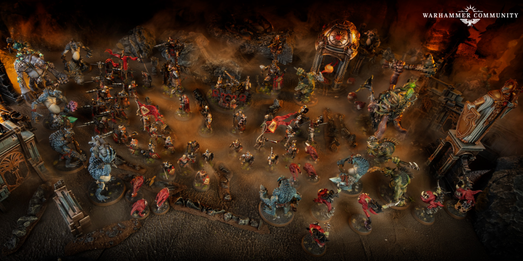 Wide tabletop Warhammer battle with many painted miniatures clashing among lava lit ruins and smoky haze logo top right