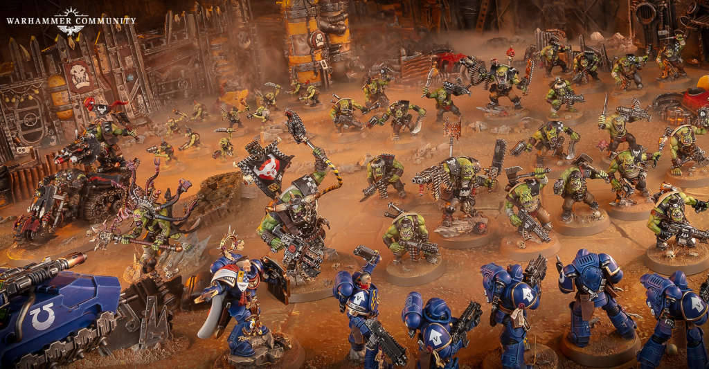 image Frontline Gaming Tabletop battle scene with dense green orc infantry fighting blue armored Space Marines amid a dusty ruined fortress and smoke filled air