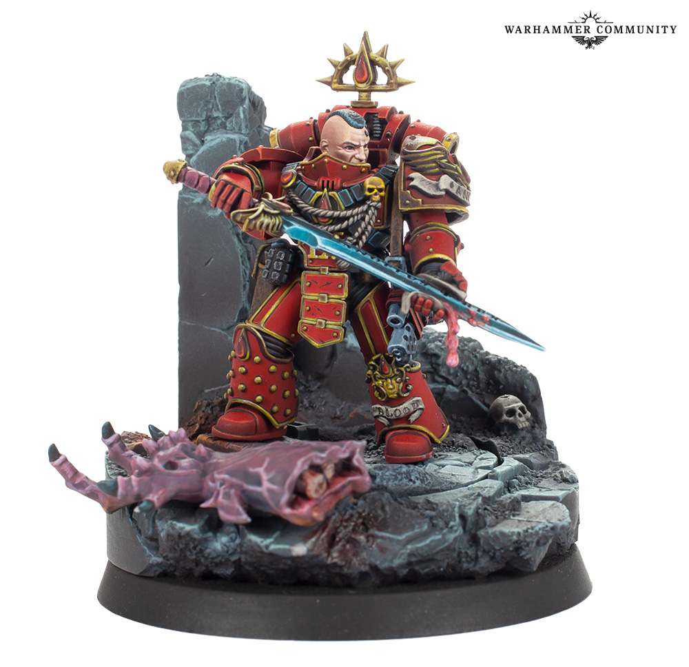 image Frontline Gaming Red armored Warhammer miniature with blue sword on rocky base standing over a pink fallen creature and skulls Warhammer Community logo top right