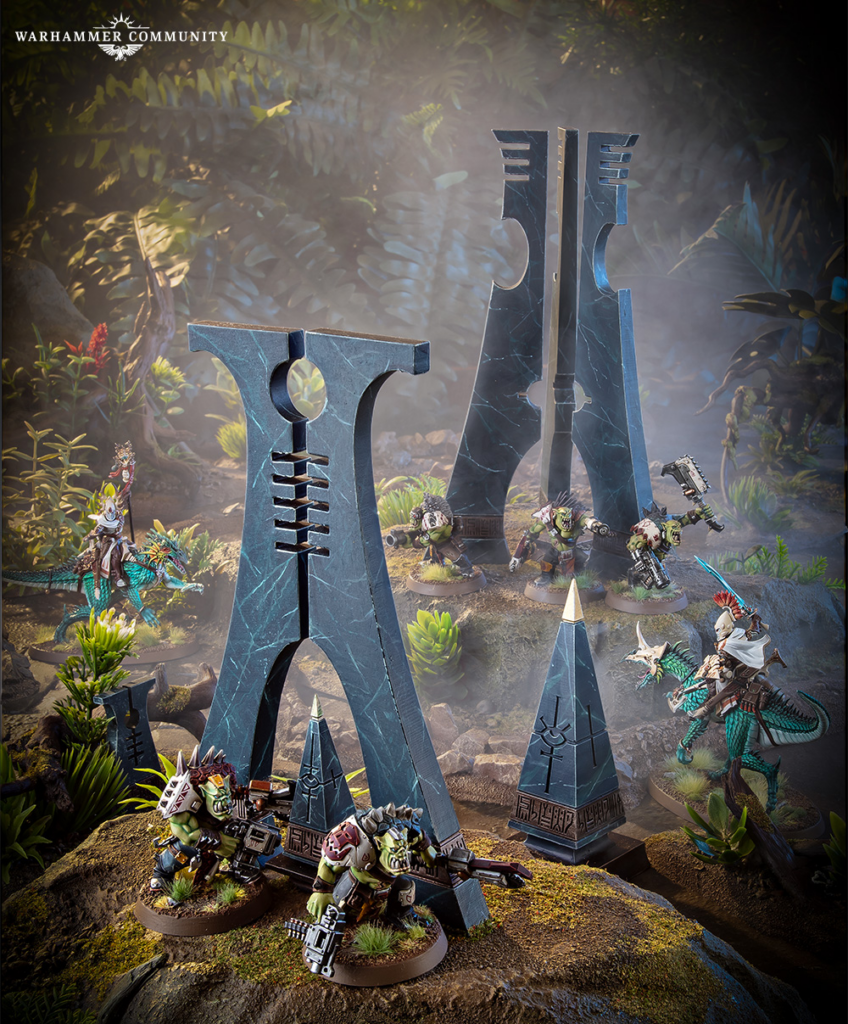 Warhammer miniature battle scene with blue stone obelisks and orc like warriors amid a forest ruins diorama