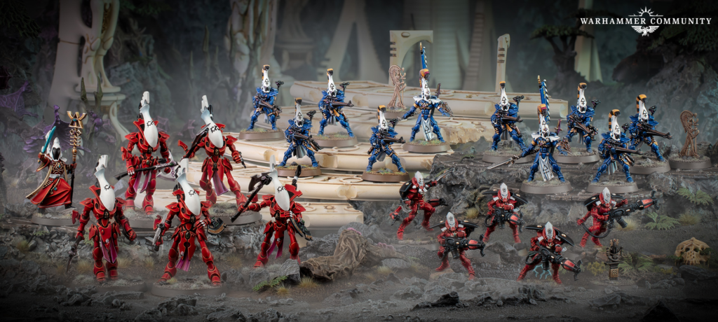 Row of red armored and blue armored Warhammer miniatures posed on a rocky ruined battlefield