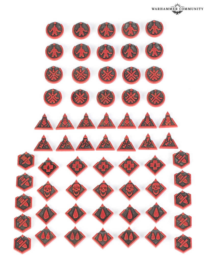 image Frontline Gaming Red and black Warhammer game tokens arranged in neat rows circular triangular and diamond shapes with various icons Warhammer Community logo in the top right corner