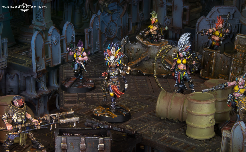 image Frontline Gaming Warhammer miniatures in a rusted industrial set central figure with colorful feathered headdress leading armed teammates