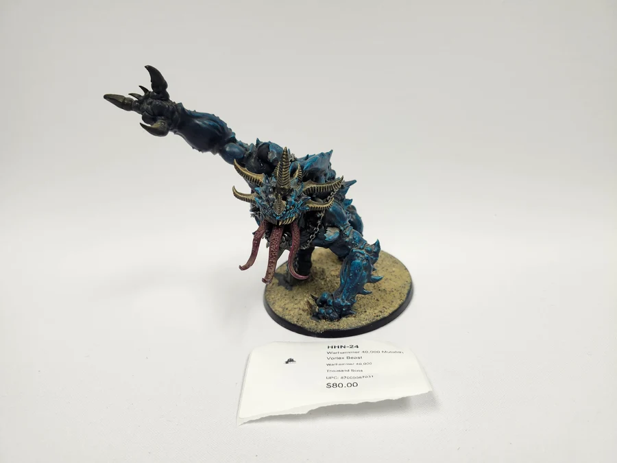 image Frontline Gaming Blue demon like fantasy miniature with multiple horns spiked limbs and a long pink tongue on a sandy base price tag visible nearby