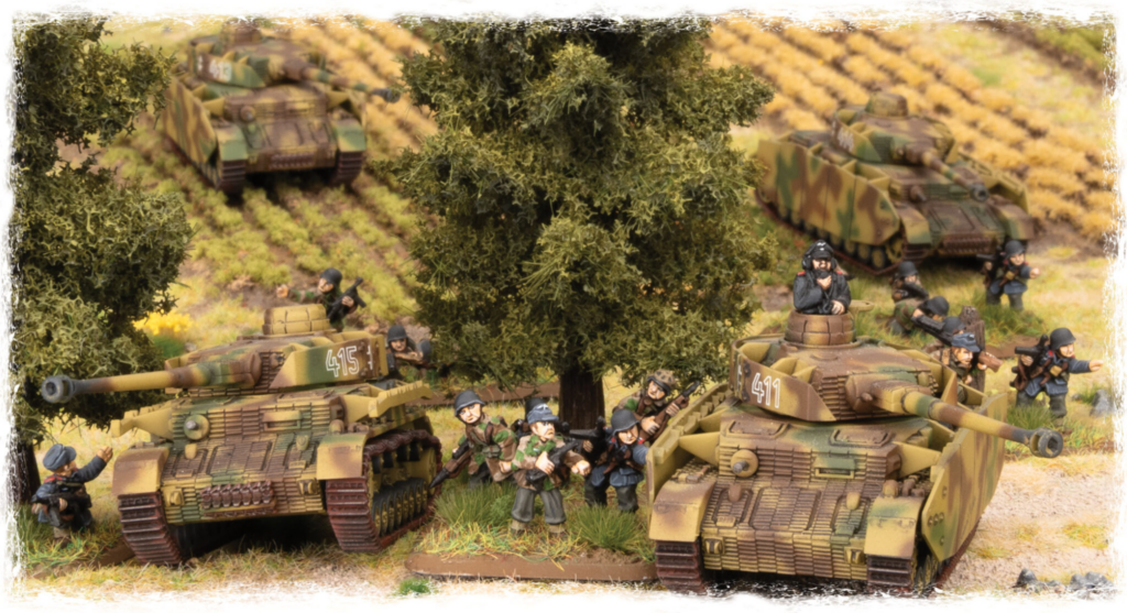 Miniature World War II battlefield scene with camouflaged tanks and toy soldiers among trees and scrub