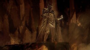 Dark armored figure with a raised arm stands on a rocky ledge in a fiery cavern filled with smoke and lava glow