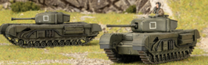 Two green military toy tanks on grass with a small figure visible in the hatch of the right tank