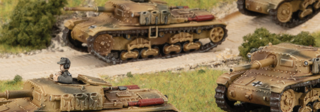 Scale model World War II battlefield scene with tan German tanks on a dusty road and a figure in an open hatch turret